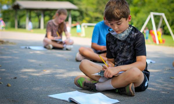 student smiles while writing on clipboard